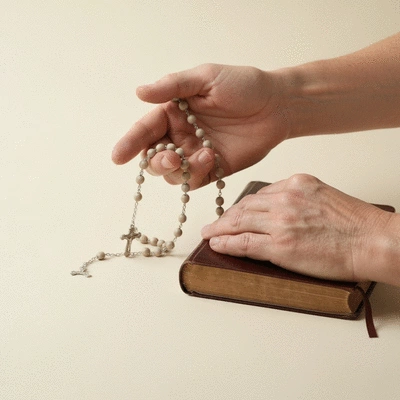 Hands holding a rosary and a Bible, symbolizing Catholic faith and doctrine
